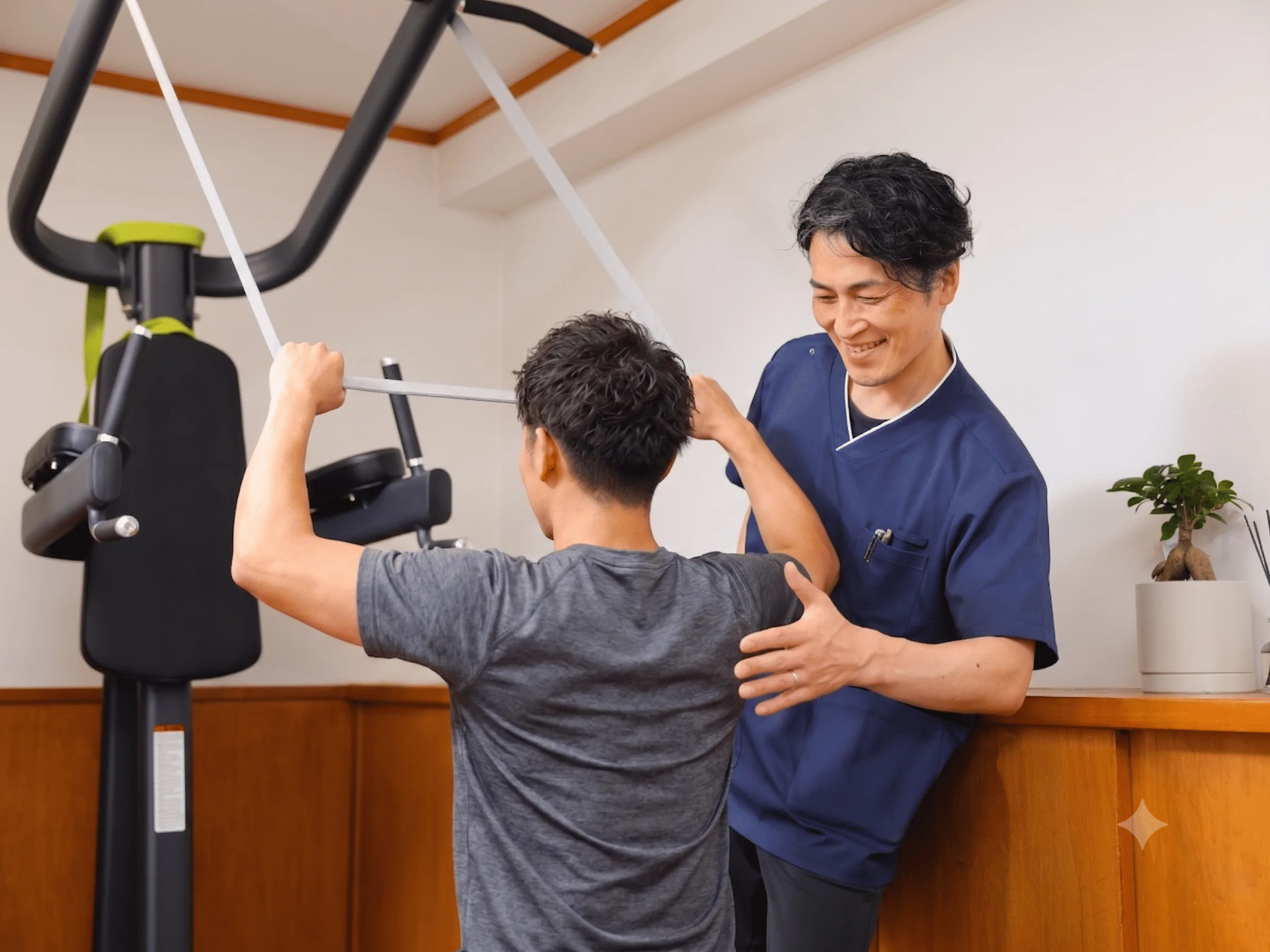 トレーニング機器を使う利用者にスタッフが姿勢を確認しながら声をかけている様子