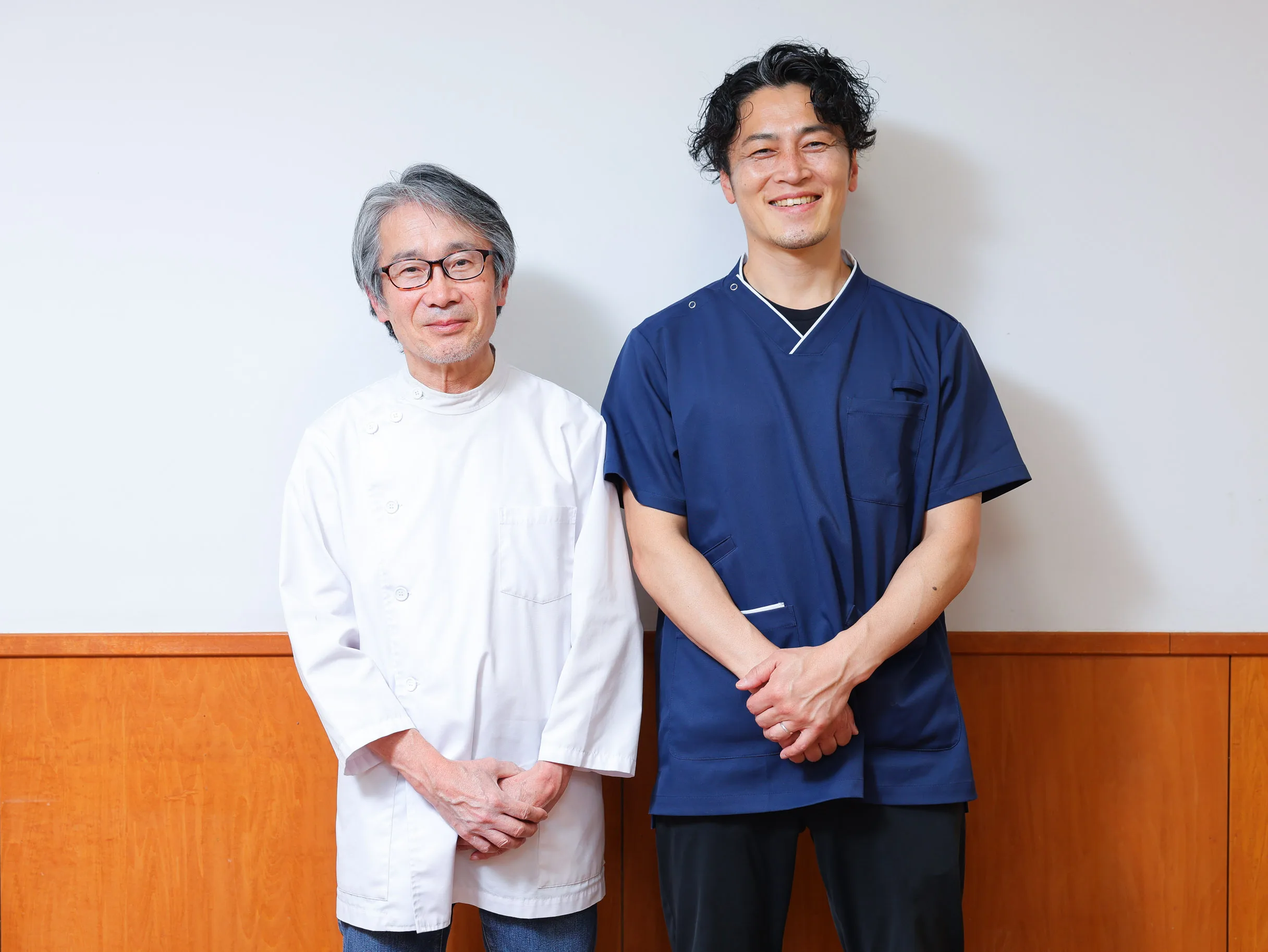 白衣と紺色の施術着を着たスタッフ2名が並んでいる写真