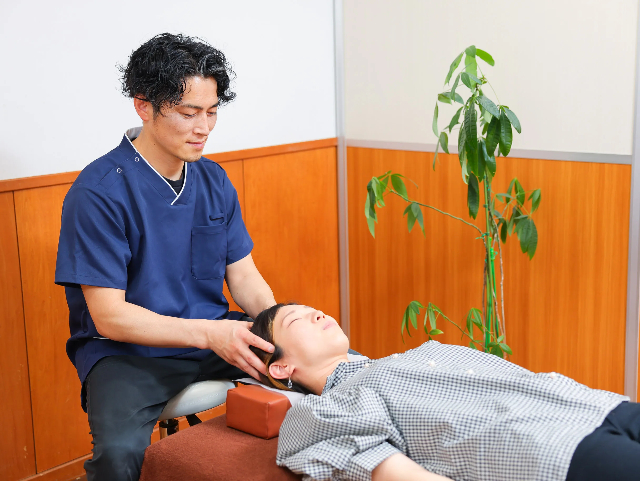 施術ベッドで利用者の首まわりに手を添えてスタッフが施術している様子