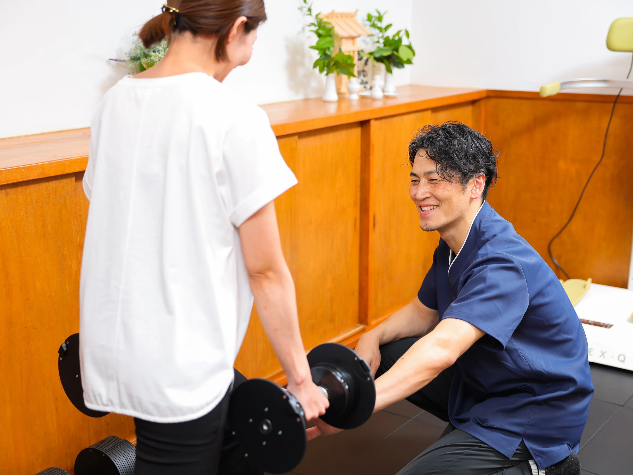 トレーニング後に利用者が姿勢を確認し、トレーナーが変化した立ち姿を一緒に見ている場面